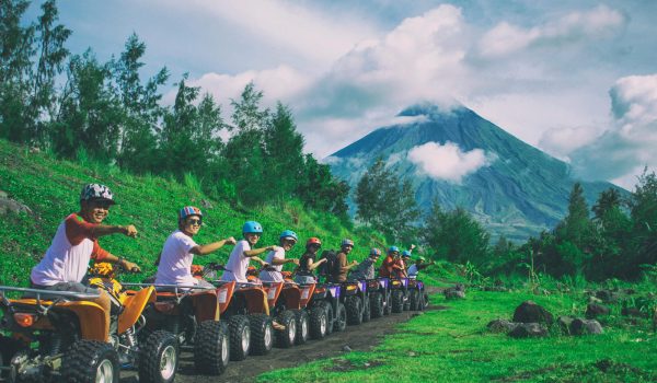 Group of friends enjoying an ATV ride with Mayon Volcano in the background.